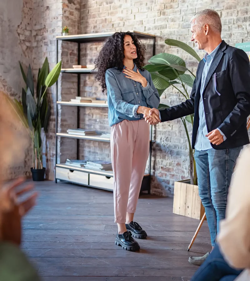 Two businesspeople congratulate shaking hands in agreement in the meeting room - in the background the diagram of the business model canvas